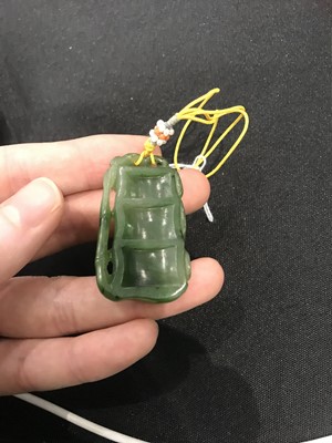 Lot 186 - A CHINESE SPINACH-GREEN JADE ‘DRAGON ON BAMBOO’ PENDANT.