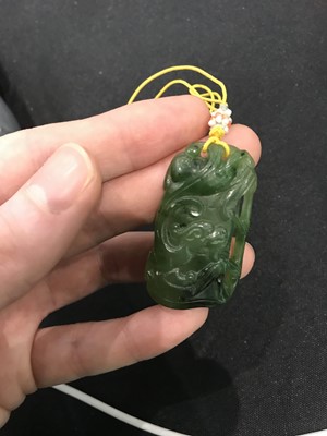 Lot 186 - A CHINESE SPINACH-GREEN JADE ‘DRAGON ON BAMBOO’ PENDANT.