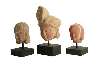 Lot 223 - THREE MOTTLED RED SANDSTONE CARVINGS OF YAKSHINI AND YAKSHA HEADS