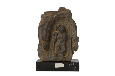 Lot 162 - A GREY SCHIST CARVING OF A FEMALE ATTENDANT UNDER AN ARCHED TORANA