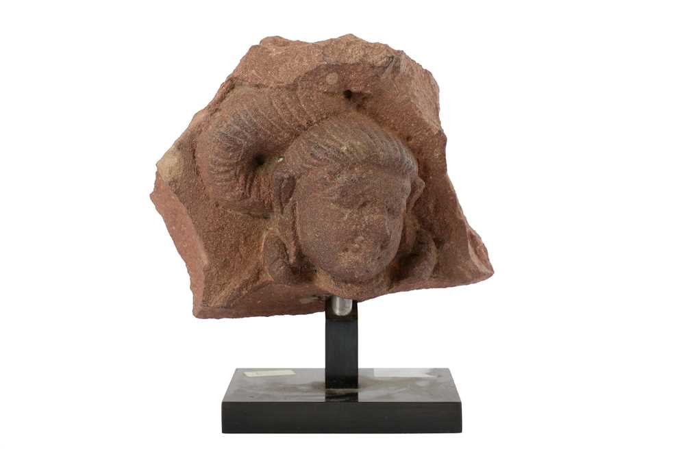 Lot 109 - A MOTTLED RED SANDSTONE CARVING OF A YAKSHINI HEAD
