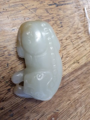 Lot 247 - A CHINESE PALE CELADON JADE ARCHAISTIC MODEL OF A LION. / A PALE CELEDON JADE CARVING OF A LION.
