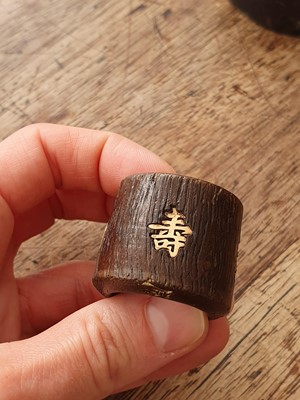 Lot 7 - A CHINESE INSCRIBED AND GOLD-INSET AGARWOOD ARCHER'S RING.