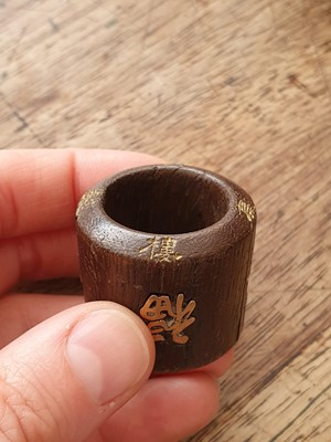 Lot 7 - A CHINESE INSCRIBED AND GOLD-INSET AGARWOOD ARCHER'S RING.