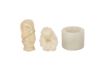 Lot 246 - TWO CHINESE PALE CELADON JADE FIGURES AND AN ARCHER'S RING.