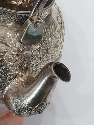 Lot 480 - A JAPANESE REPOUSSÉ SILVER 'CHRYSANTHEMUM' TEAPOT AND COVER.