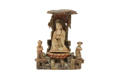 Lot 328 - A CHINESE SOAPSTONE CARVING OF A GUANYIN IN A GROTTO WITH TWO ATTENDANTS.
