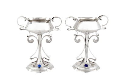 Lot 551 - A pair of Edwardian ‘Arts and Crafts’ sterling silver twin handled cups, Sheffield 1907 by Mappin and Webb