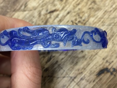 Lot 110 - A CHINESE BLUE-OVERLAY BEIJING GLASS 'CHILONG' BANGLE