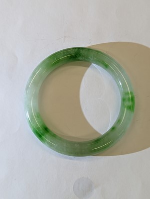 Lot 536 - A CHINESE PALE-CELADON AND APPLE-GREEN JADE BANGLE