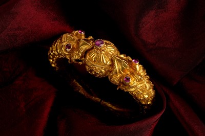 Lot 298 - A RUBY-SET 'MAKARA HEAD' GOLD BANGLE (KADA)