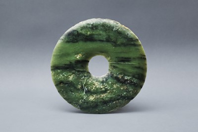 Lot 193 - A CHINESE ARCHAIC MOTTLED GREEN JADE DISC, BI