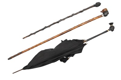 Lot 324 - TWO WALKING CANES AND AN UMBRELLA WITH CARVED EBONY HEADS, EARLY 20TH CENTURY