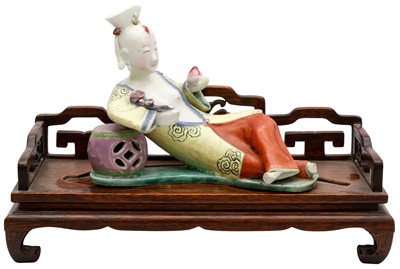 Lot 87 - A CHINESE FAMILLE-ROSE FIGURE OF A RECUMBENT LADY RECLINING ON A WOOD BED