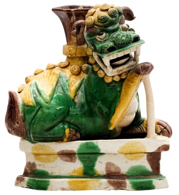 Lot 30 - A CHINESE BISCUIT SANCAI-GLAZED 'LION DOG' CANDLE HOLDER