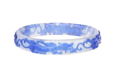 Lot 219 - A CHINESE BLUE-OVERLAY BEIJING GLASS 'CHILONG' BANGLE