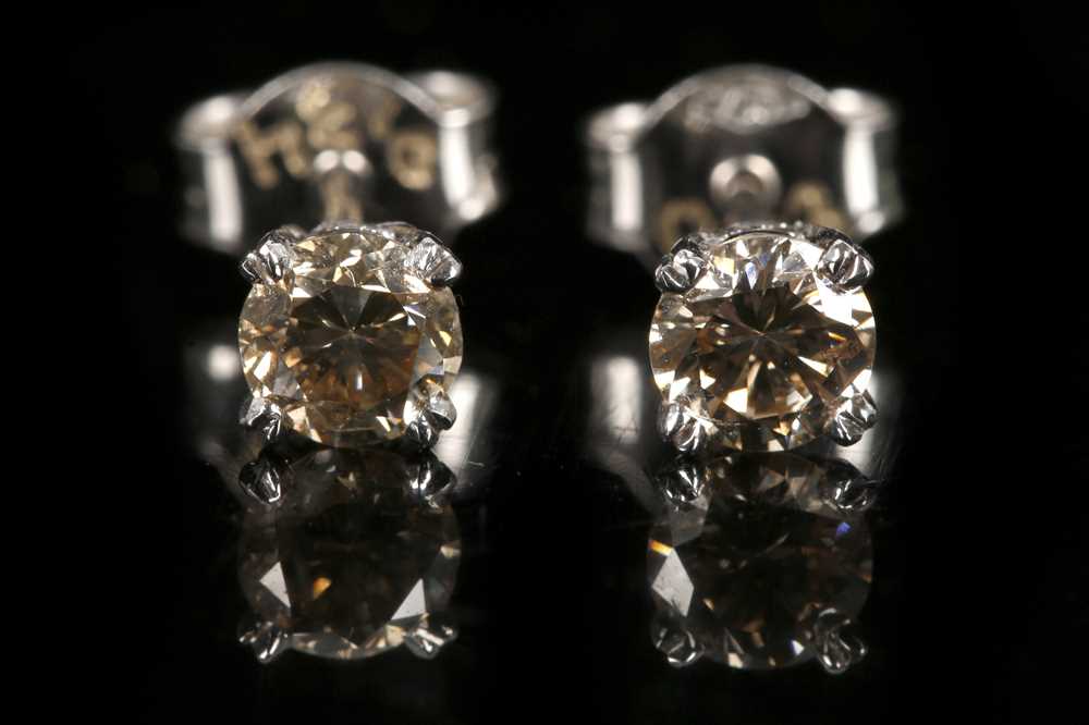 Lot 555 - A pair of 18ct white gold, champagne diamond...