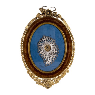 Lot 423 - A silver filigree mounted reliquary in an oval gilt metal frame
