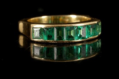 Lot 585 - An 18ct yellow gold and emerald ring, channel...