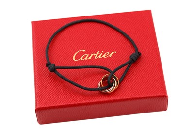 Lot 51 - A "Trinity" cord bracelet by Cartier,...